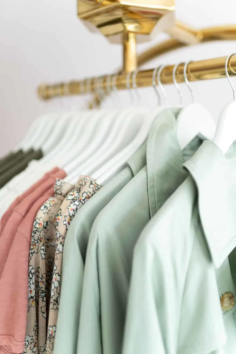 A collection of clothes in green and earthy colors hanging on a rack