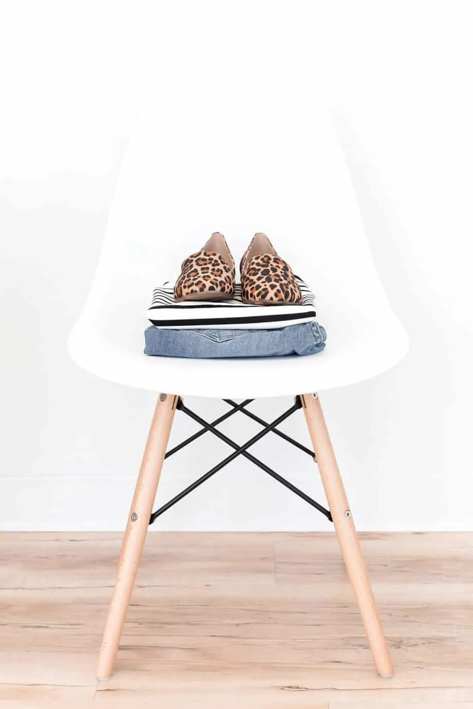 An outfit folded and sat on a white stool with a pair of shoes on top.